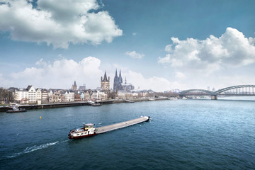 Naklejka premium Cologne cityline with cargo ship on rhine