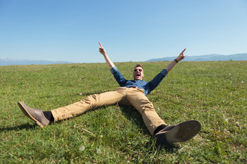 casual man laying in the grass and cheering