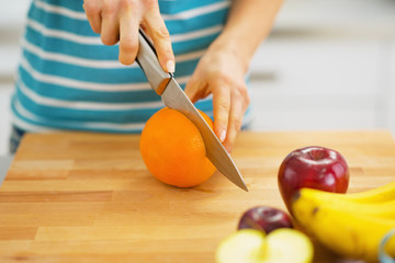Closeup on young woman cutting orange