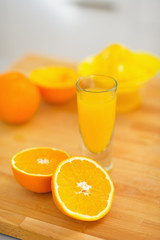 Closeup on glass of orange juice and oranges on cutting board