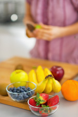 Closeup on fruits on cutting board and housewife in background