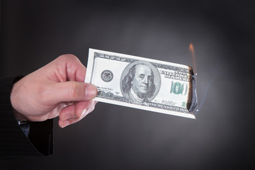 Close-up Of Hand Holding Burning Banknote