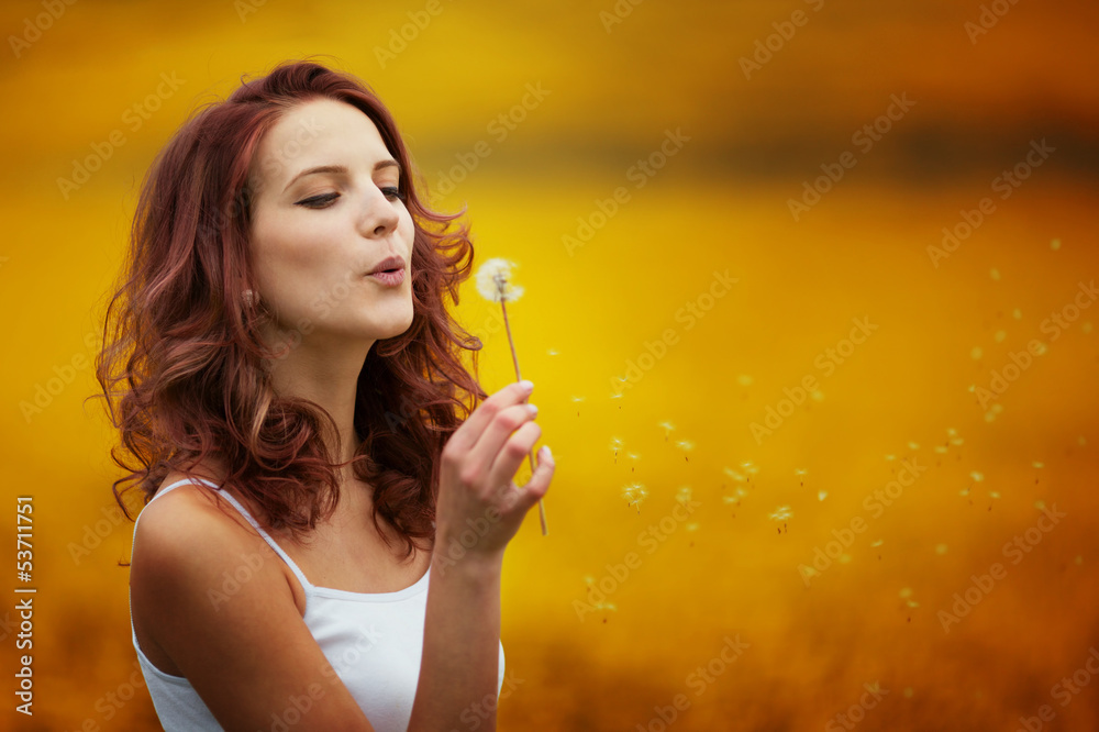 Wall mural happy beautiful woman blowing dandelion