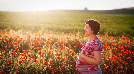 Pregnant woman in a flowering poppy field