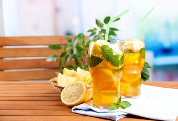 Iced tea with lemon and mint on wooden table, outdoors