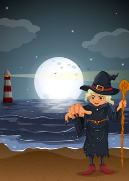 An old witch holding a stick at the beach