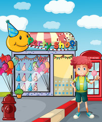A boy holding a lollipop outside the party shop