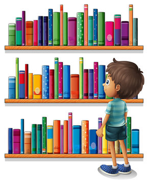 A boy in the library in front of the bookshelves