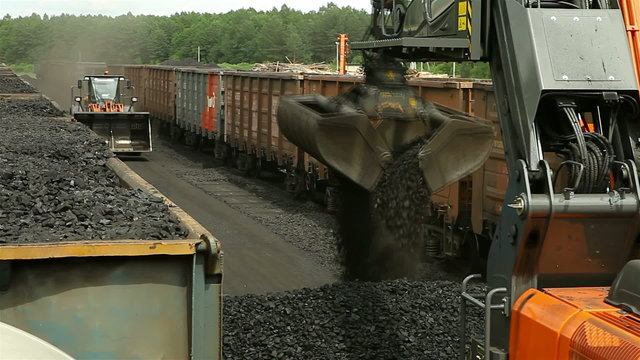 excavators, unloading coal from a cargo train.