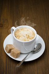 cup of black coffee with foam and cane sugar cubes
