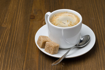 cup of black coffee with foam and cane sugar cubes, horizontal
