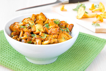 Fried autumn golden chanterelle mushrooms with herbs in bowl