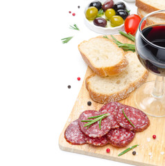 salami, bread, olives, glass of wine on wooden board isolated