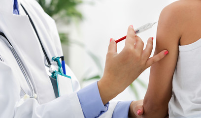 Female doctor making injection to little boy