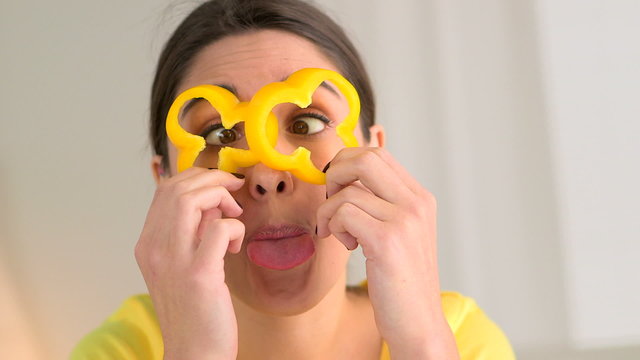 Happy  woman making silly faces with bell peppers over eye