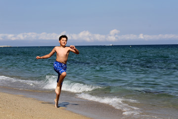 Boy running on the sea beach on summer holidays