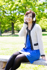 young asian woman listening music in the park