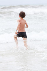 kleiner junge spiel glücklich im sand am meer im wasser