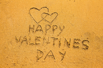 In the beach sand: Happy Valentine's Day and two hearts
