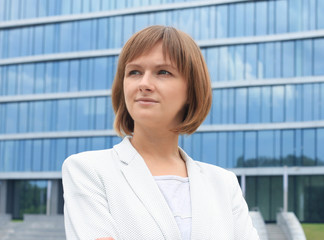 Fototapeta premium Portrait of young business woman on building background