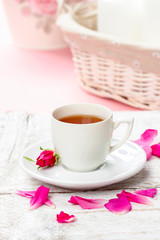 Cup of tea decorated with rose petals in pink table setting