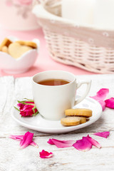 Fototapeta na wymiar Cup of tea decorated with rose petals in pink table setting