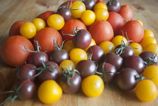 Various types of tomatoes on wooden background