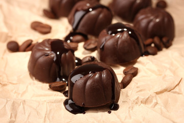 Chocolate candies and coffee beans, on beige paper background