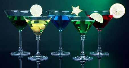 Alcoholic cocktails in martini glasses on dark green background