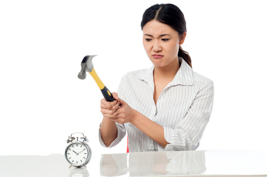 Frustrated woman smashing an alarm clock