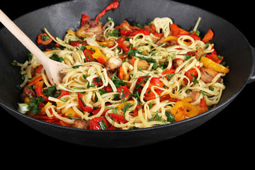Noodles with vegetables on wok isolated on black