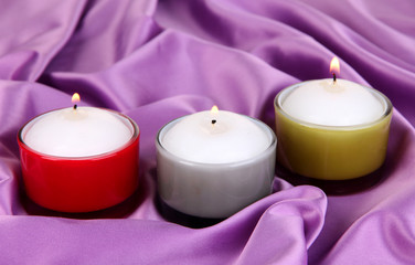 Obraz na płótnie Canvas Candles on purple fabric close-up