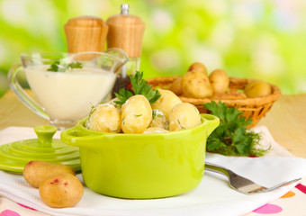Tender young potatoes with sour cream and herbs in pan