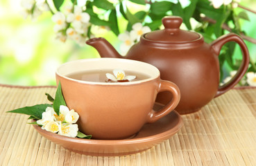 Cup of tea with jasmine, on bamboo mat, on bright background