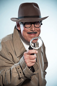 Vintage detective with mustache and hat. Looking through magnify