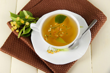Cup of tea with linden on napkin on  wooden table