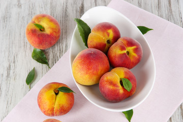 Peaches in plate on napkin on wooden table