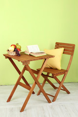 Wooden table with fruit and book on it in room
