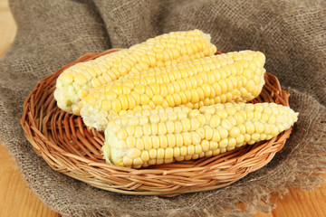 Fresh corn on wicker mat, on sackcloth background