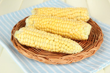 Fresh corn on wicker mat, on wooden background