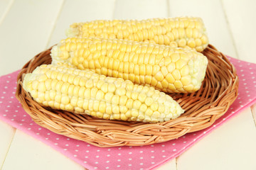 Fresh corn on wicker mat, on wooden background