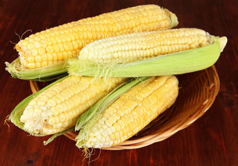 Fresh corn vegetable in wicker basket on wooden table