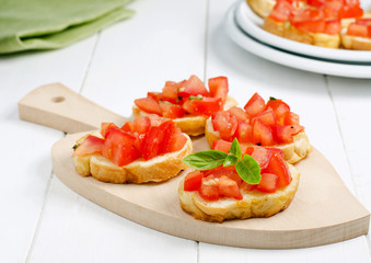 Fresh bruschetta with tomato and basil on cutting board