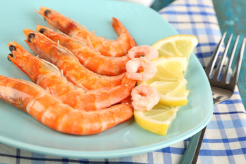 Shrimps with lemon on plate on wooden table close-up