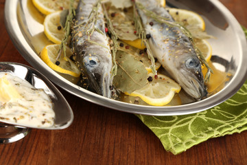 Fish in frying pan with spices and lemon