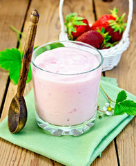 Milkshake with strawberries and spoon on the board