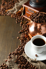Naklejka premium Cup of coffee, pot and grinder on wooden background