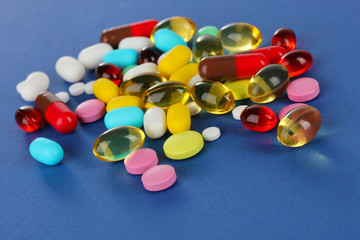 Assortment of pills, tablets and capsules on blue background