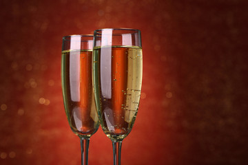 Two glasses of champagne on bright background with lights