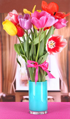 Beautiful tulips in bouquet on table in room